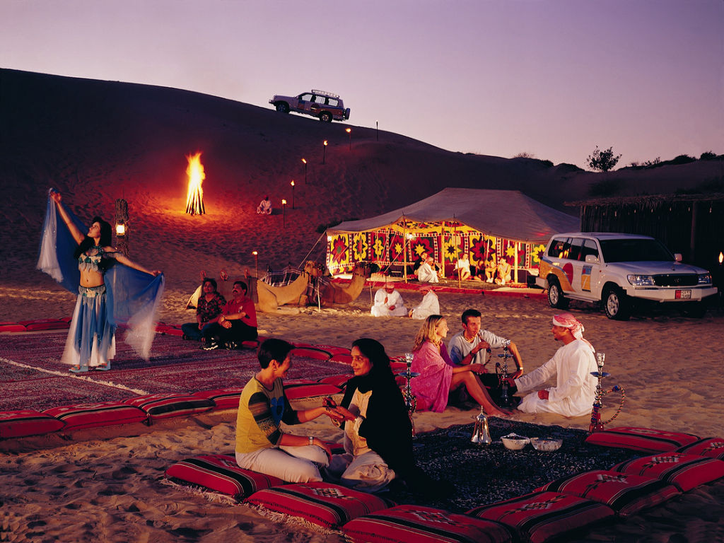 Travellers around a desert camp at dusk